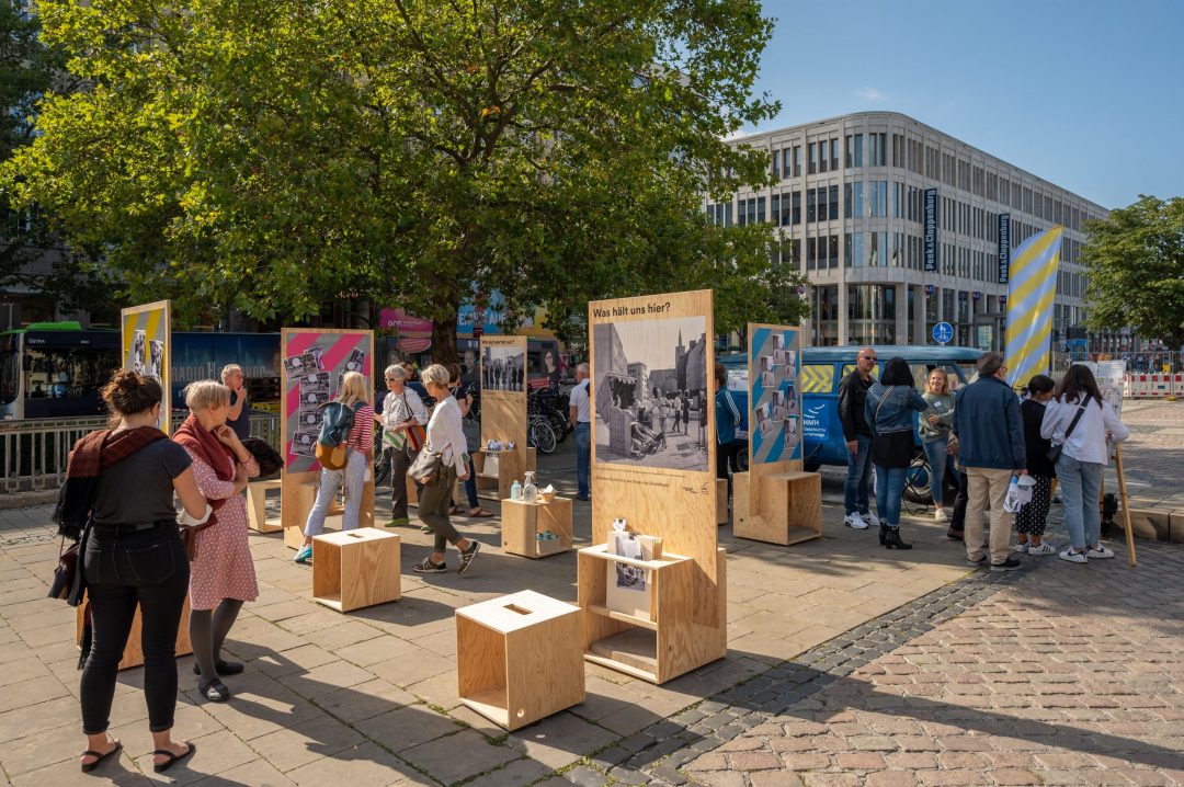 Outdoor-Ausstellung „Geschichte unterwegs“ mit Holzaufstellern, historischen Fotos und Beteiligung im öffentlichen Raum Hannovers.