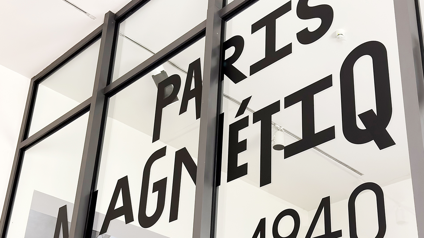 Ausstellungstitel „Paris Magnétique“ in schwarzen Buchstaben auf Glas geplottet