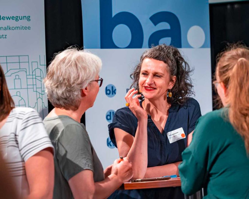 Drei Personen vor Roll-up ba Wolfenbüttel. Angeregt diskutierende Personen