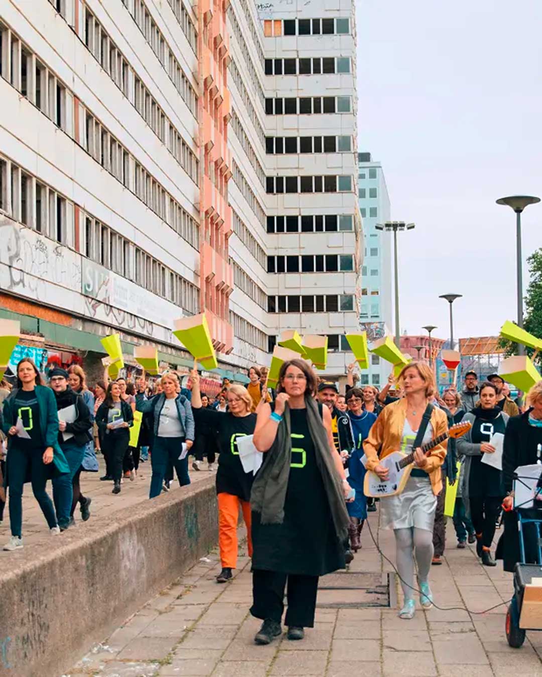 Demonstration/ Menschenansammulung. Die Anwesenden halten gelbe Papp-Konstruktionen, welche aussehen wie Megafone.