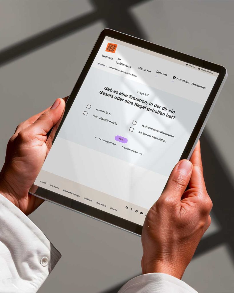 Blick über die Schulter einer Person mit Tablet. Website Beteiligung Formum Recht mit Multiple Choice Frage