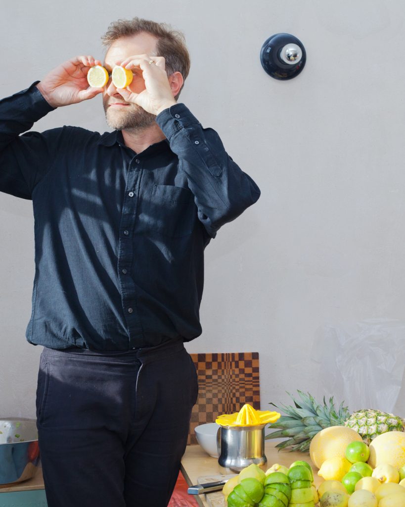 Eine Person in schwarzer Kleidung hält sich Zitronenhälften vor die Augen wie ein Fernglas und schaut in die Ferne