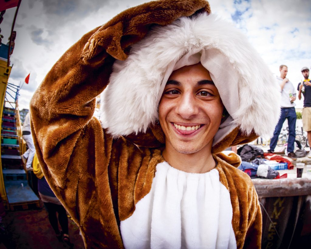 Eine Person im Hasenkostum schiebt sich die Maske vom Kopf und streckt lächelnd die Zunge zwischen den Zähnen hinaus.