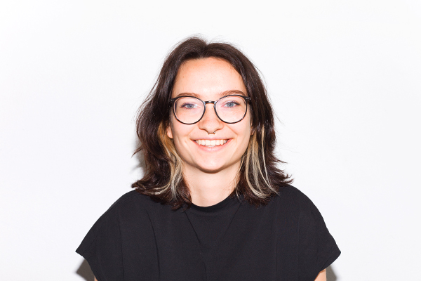 Portrait von Cecilie Behr, braunhaarige Person mit blonden Strähnen, schwarzem Shirt und Brille