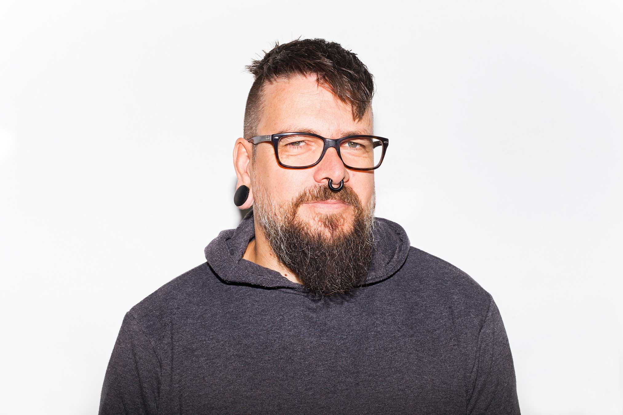 Portrait von Guido Handrick, braunhaarige Person mit schwarzem Kapuzenshirt, Brille und Bart