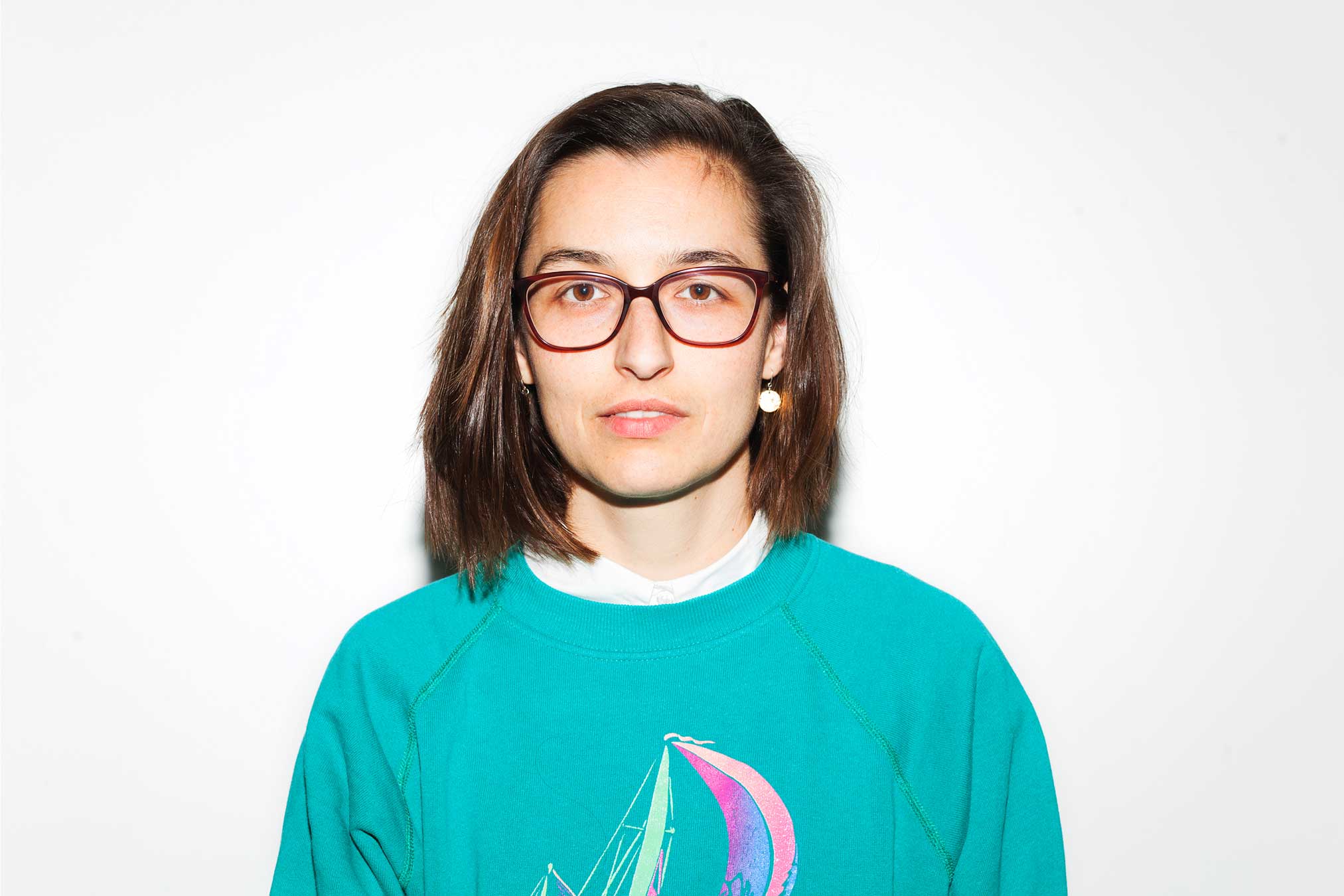 Portrait von Marie Breinl, braunhaarige Person mit türkisenem Shirt und Brille