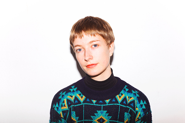 Portrait von Wencke Hamann, blonde Person mit schwarzem Shirt und türkisenem Muster mit gelben Details