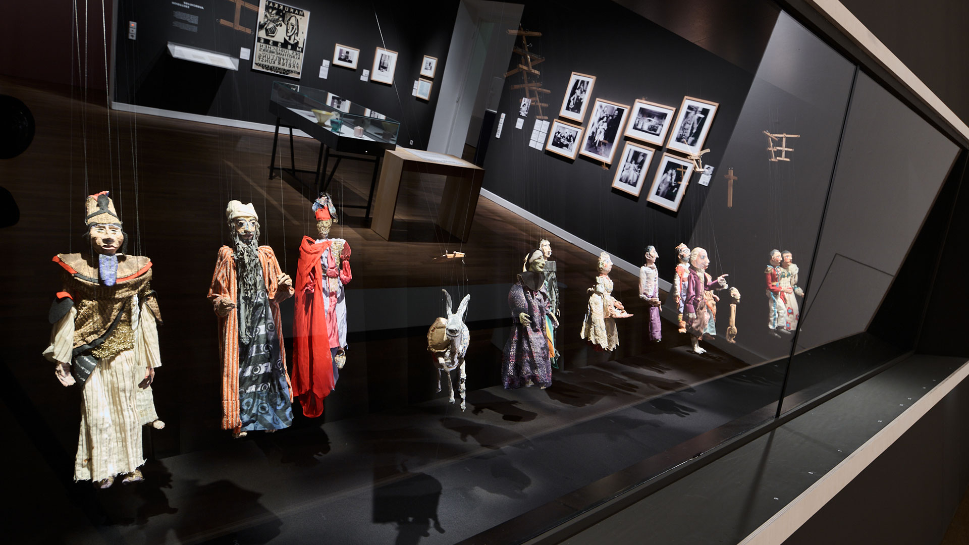 Raumansicht Ausstellung Widerstände. Vitrinenwand mit Handpuppen. Im Glas spiegelt sich die Raumansicht.