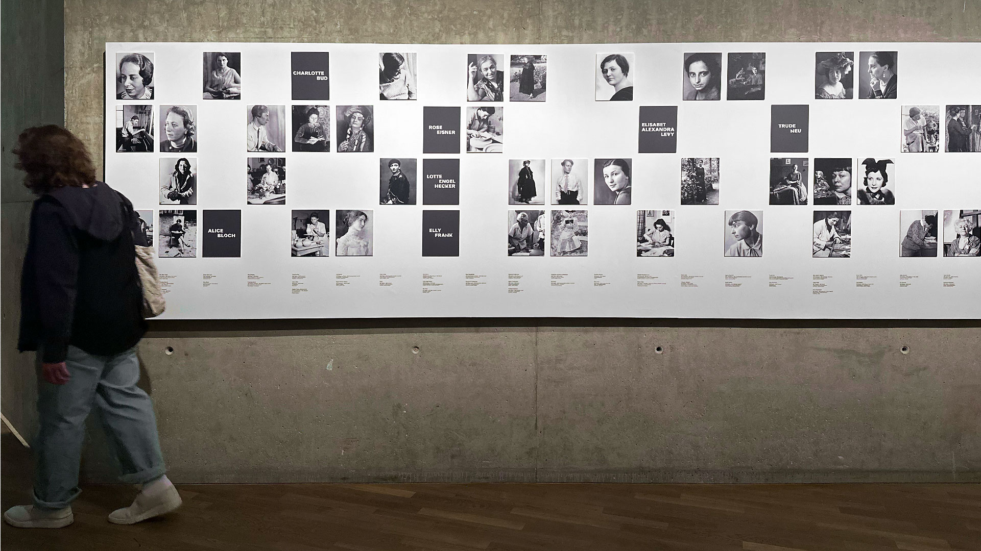 Wandansicht der Ausstellung Widerstände. Schwarzweiss-Portraits von Designerinnen auf weißem Grund. Im Hintergrund eine Waschbetonwand.