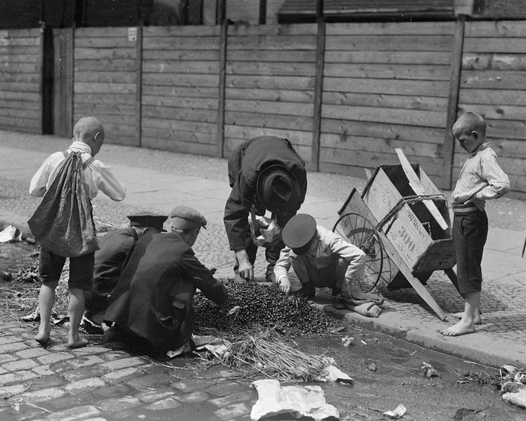 Historische Aufnahme, schwarzweiß, ca. 1920. Mehrere Personen bücken sich nach Verwertbarem