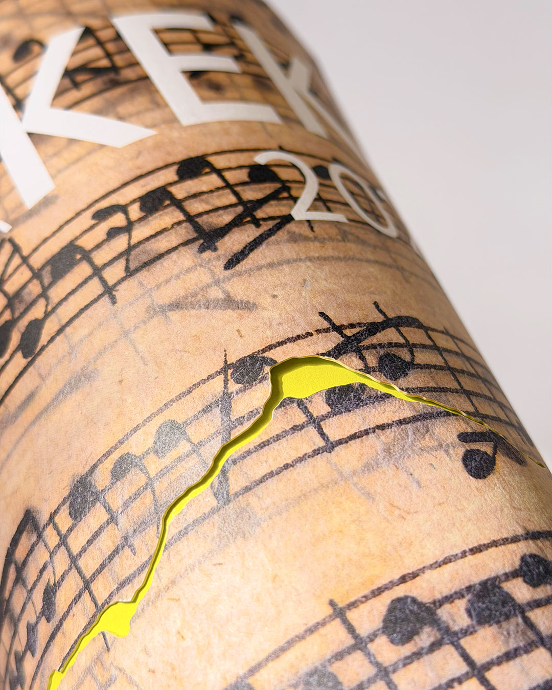 Zusammengerolltes Magazin mit Veredelung auf dem Cover. Bildmotiv Notenblatt mit Papierschäden. Durch die Veredelung scheint hellgrüner Schmutztitel.