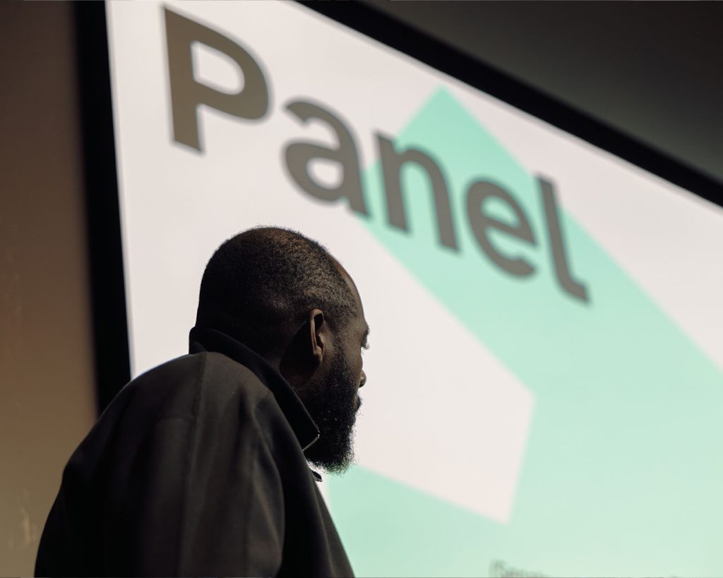 Eine Person vor Bühnenprojektion mit dem Titel Panel